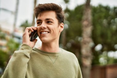 Genç İspanyol adam gülümsüyor. Şehirdeki akıllı telefondan konuşuyor..