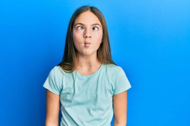 Güzel, esmer, beyaz tişört giyen dudaklı balık suratı yapan, çılgın ve komik bir jest yapan küçük bir kız. Komik ifade. 