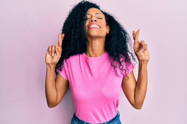 Orta yaşlı Afro-Amerikalı kadın sıradan kıyafetler giyip umut ve gözlerin kapalı gülümseyerek el sallıyor. Şans ve batıl inançlar. 