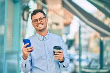 Genç İspanyol işadamı akıllı telefon kullanıyor ve şehirde kahve içiyor..