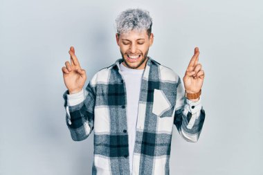 Modern boyalı saçları olan, sıradan gömlekler giyen, umut ve gözleriyle gülümseyerek el hareketi yapan genç İspanyol bir adam. Şans ve batıl inançlar. 