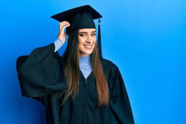Mezuniyet şapkası ve tören cübbesi takan güzel esmer bir kadın soru sorup kafasını karıştırıyor. Şüpheyle kararsız, kafa kafaya düşünerek. Düşünceli kavram. 