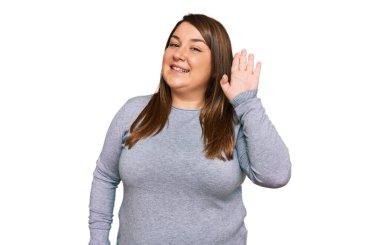 Güzel esmer ve cüsseli bir kadın gündelik kıyafetler giyip merhaba diyor mutlu ve gülümsüyor, dostça karşılama hareketi yapıyor. 