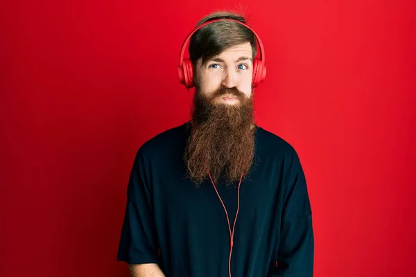 Uzun Sakallı Kulaklıkla Müzik Dinleyen Komik Suratlı Kızıl Saçlı Adam — Stok fotoğraf
