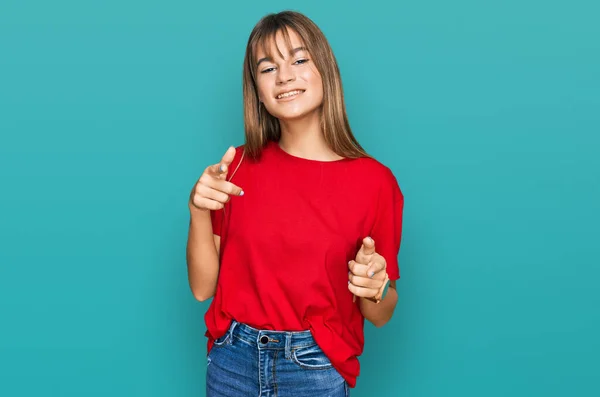十代の白人の女の子は 幸せと面白い顔をしたカメラに指を指してカジュアルな赤いTシャツを着ています 良いエネルギーと振動は — ストック写真