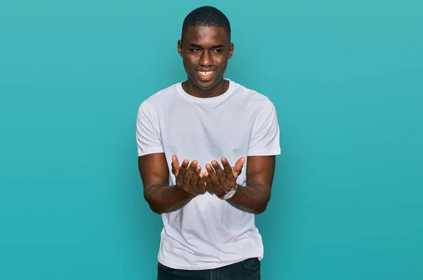 年轻的非洲裔美国人 身穿休闲的白色T恤 手牵着手微笑着接受或给予的手势 持有和保护 — 图库照片