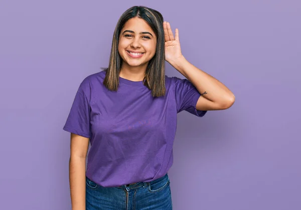 年轻的惊慌失措的女孩穿着宽松的紫色T恤 双手相对地微笑着 聆听谣言或流言蜚语 聋的概念 — 图库照片