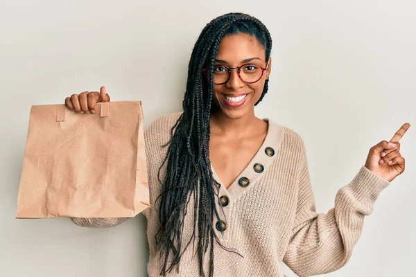 アフリカ系アメリカ人の女性は手と指で側に幸せなポインティング笑顔紙袋を取ります — ストック写真