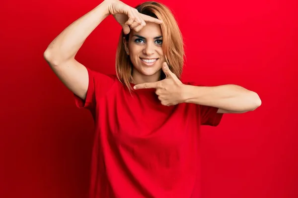 カジュアルな赤いTシャツを着たヒスパニック系の若い女性が幸せな顔で手や指でフレームを作り笑顔 創造性と写真の概念 — ストック写真