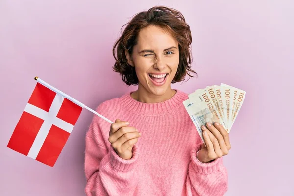 Młoda Brunetka Kobieta Trzyma Norweską Flagę Korona Banknoty Mruga Patrząc — Zdjęcie stockowe