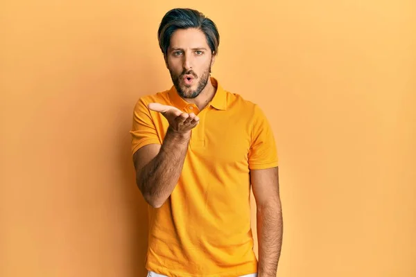 Joven Hombre Hispano Vistiendo Casual Camiseta Amarilla Mirando Cámara Soplando — Foto de Stock