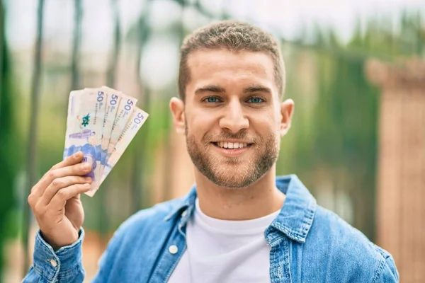 Jovem Caucasiano Sorrindo Feliz Segurando Pesos Colombianos Cidade — Fotografia de Stock