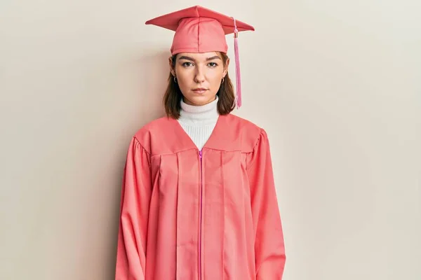 年轻的高加索女人头戴毕业帽 身穿婚纱 脸上露出严肃的表情 简单而自然地看着相机 — 图库照片