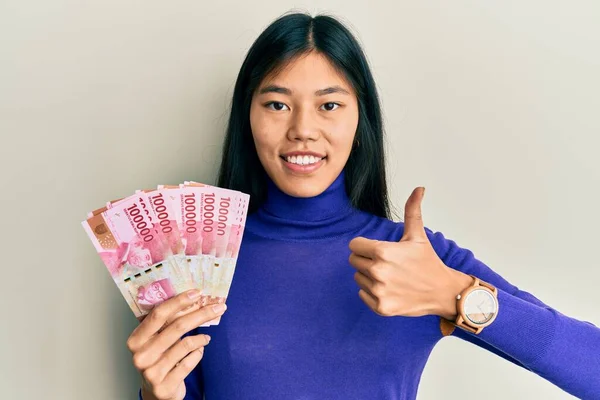 Ung Kinesisk Kvinna Som Innehar Indonesiska Rupiah Sedlar Ler Glad — Stockfoto