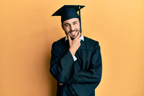 卒業キャップと式のローブを着た若いヒスパニック系の男は カメラを見て自信を持って交差腕とあごに提起手で笑顔 ポジティブな — ストック写真