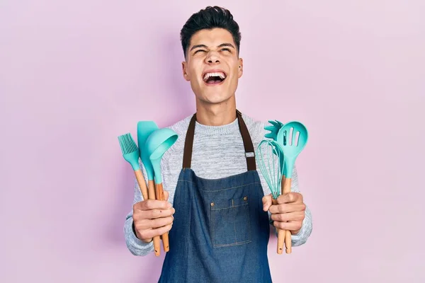 Jovem Hispânico Vestindo Avental Profissional Padeiro Segurando Ferramentas Cozinha Irritado — Fotografia de Stock