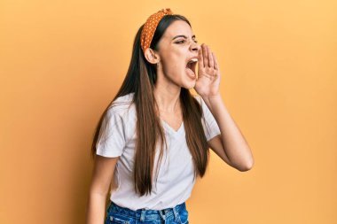 Güzel esmer, beyaz tişört giyen genç bir kadın el ve ağızla bağırıyor ve çığlık atıyordu. iletişim konsepti. 