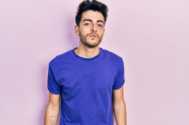 Latin asıllı genç bir adam, sıradan bir tişört giyip kameraya bakıyor ve canlı yayında öpüşüyor. Güzel ve seksi. aşk ifadesi. 