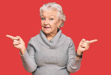 Kış süveteri giyen yaşlı gri saçlı kadın farklı yönleri gösteren kendine güvenle gülümsüyor. reklam için kopyalama alanı 