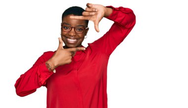 Gündelik kıyafetler ve gözlük takan, gülümseyen, elleri ve parmakları mutlu yüzlü genç Afro-Amerikan kadın. yaratıcılık ve fotoğrafçılık kavramı. 