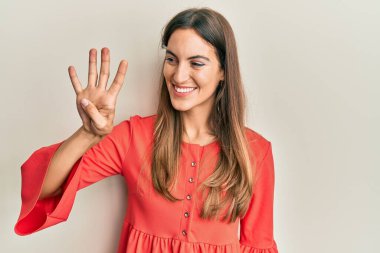 Genç ve güzel bir kadın gündelik giysiler giyer ve parmaklarını dört numaraya gösterir ve gülümserken kendinden emin ve mutludur.. 