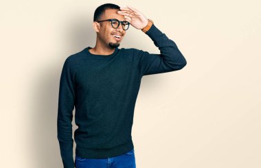 Gündelik kıyafetler ve gözlük takan genç Afro-Amerikan bir adam çok mutlu ve tebessüm ediyor. arama kavramı. 