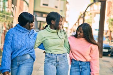 Üç Afrikalı Amerikalı arkadaş gülümsüyor. Mutlu bir şekilde kucaklaşıyorlar..