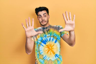 Günlük giysiler giyen genç İspanyol adam korku ifadesinden korkuyor ve dehşete düşüyor. El hareketlerini durdur, şok içinde bağır. panik konsepti. 