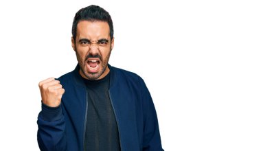 Latin asıllı genç bir adam, kızgın ve kızgın. Öfkeyle bağırırken yumruğunu sallıyor ve öfkeleniyor. öfke ve agresif konsept. 