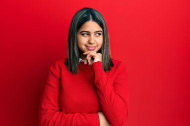 Elleri çenesinde gündelik kıyafetler giyen, soru soran genç Latin bir kadın. Düşünceli bir ifade. Düşünceli bir yüzle gülümsüyor. şüphe kavramı. 