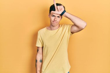 Latin asıllı genç bir adam günlük sarı tişört giyiyor. Alnında parmakları olan insanlarla dalga geçiyor. Ezik hareketler yapıyor, alay ediyor ve hakaret ediyor.. 