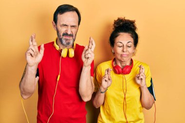 Orta yaşlı bir çift İspanyol kadın ve spor giysisi ve kolluk takan bir adam umut ve gözleri kapalı gülümseyerek el sallıyorlar. Şans ve batıl inançlar. 