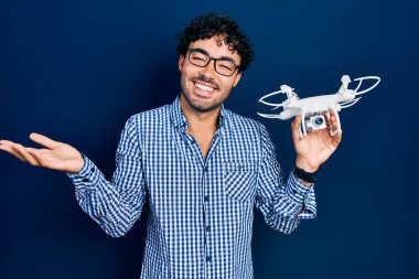 İspanyol asıllı genç adam başarıyı kutlamak için İHA 'yı tutarken mutlu bir gülümseme ve elini kaldırarak kazanan bir ifade takındı. 