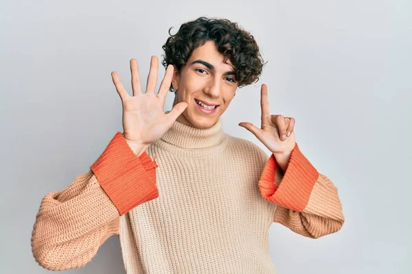 Hispanik genç adam günlük kazak giyiyor ve yedi numaralı parmaklarıyla işaret ederken kendinden emin ve mutlu gülümsüyor.. 