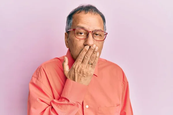 Middle age indian man wearing casual clothes and glasses bored yawning tired covering mouth with hand. restless and sleepiness.