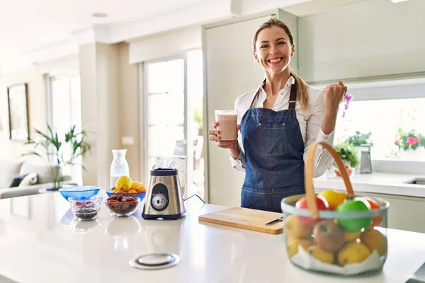 Güzel Sarışın Kadın Önlük Giyip Mutfakta Smoothie Içiyor Gururla Bağırıyor — Stok fotoğraf
