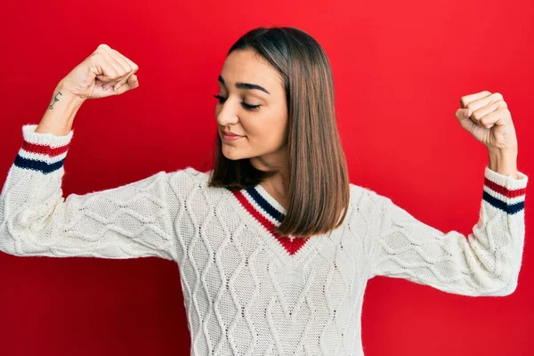 腕の筋肉を示すカジュアルな学生のセーターを着て若いブルネットの女の子は誇りに思って笑顔 フィットネスのコンセプト — ストック写真