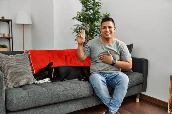 Jovem Latino Homem Cão Sentado Sofá Casa Sorrindo Jurando Com — Fotografia de Stock