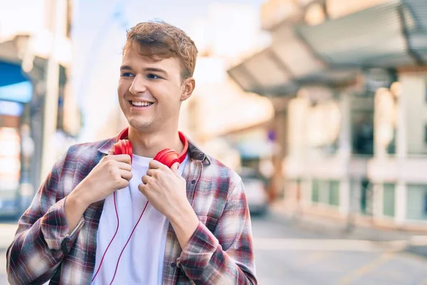 Νεαρός Καυκάσιος Άνδρας Χαμογελά Χαρούμενος Χρησιμοποιώντας Ακουστικά Στην Πόλη — Φωτογραφία Αρχείου