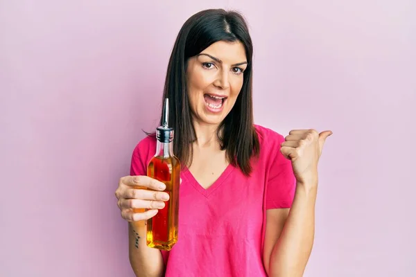 Young Hispanic Woman Holding Olive Oil Can Pointing Thumb Side — Stock Photo, Image