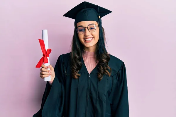 若いですヒスパニック系の女性を着て卒業制服を保持卒業証書見て正と幸せな立ちと笑顔で自信を持って笑顔示す歯 — ストック写真