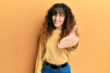 Gündelik kıyafetler giyen genç İspanyol kız dostça bir selamlama ve hoş geldin hediyesi olarak el sıkışmayı sunuyor. başarılı iş. 