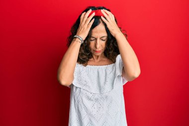 Orta yaşlı İspanyol kadın gündelik giysiler giyiyor. Baş ağrısı çekiyor, çaresiz ve stresli. Çünkü acı ve migren ağrısı var. Eller başının üstünde.. 