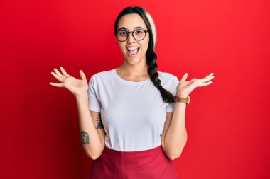 Genç İspanyol kadın profesyonel garson önlüğü giyip çılgınlığı kutluyor ve başarıyı kolları açık ve gözleri açık heyecanla haykırarak kutluyor. Kazanan konsept 