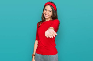 Genç esmer kadın gündelik kıyafetler giyiyor. Gülümsüyor. Avuç içi dolusu yardım eli uzatıyor ve kabul ediyor.. 