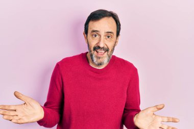 Orta yaşlı İspanyol bir adam, gündelik kıyafetler giyiyor, elleri ve kolları havada, kafası karışmış bir ifade takınıyor. şüphe kavramı. 