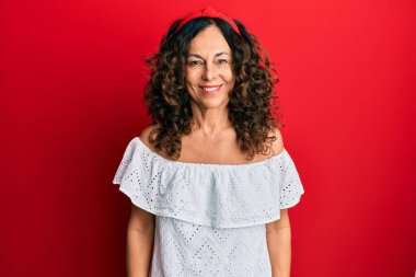 Orta yaşlı İspanyol kadın mutlu ve havalı bir gülüşü olan sıradan kıyafetler giyiyor. şanslı kişi. 