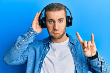 Kafkasyalı genç bir adam kulaklık takıyor ve rock sembolü yapıyor. Depresyonda ve endişe içinde, sinirli ve korkmuş. hüzünlü ifade. 