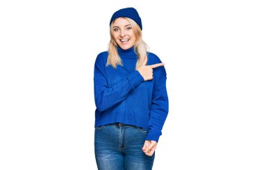 Kafkasyalı genç bir kadın yün kazak giyiyor ve neşeli bir şapka takıyor. Yüzünde mutlu ve doğal bir ifadeyle, elleri ve parmaklarıyla yüzünü gösteren bir gülümseme var. 