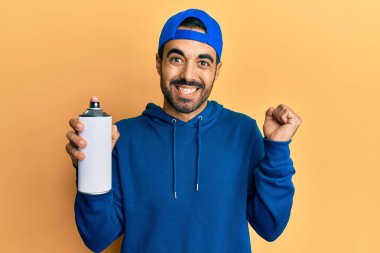 Süveter giyen genç İspanyol adam elinde grafiti spreyi ile gururla bağırıyor zaferi ve başarıyı kutluyor. 